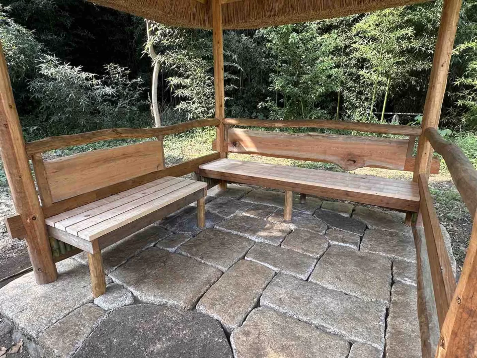 茅ヶ崎市の茅葺きの四阿施工中の風景、ヒノキ板の腰掛とケヤキの背もたれを造り付けた様子
