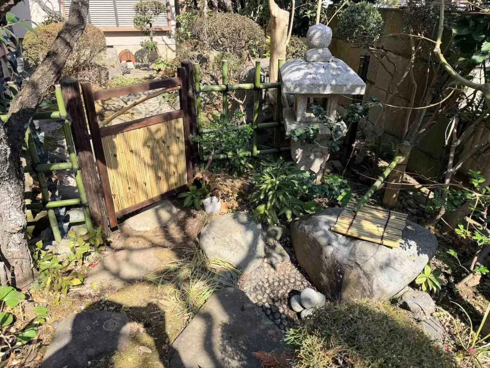 大磯の露地改修工事で、完成した四目垣の仕切りと女竹貼りの庭木戸に、筧と井戸蓋も新調した様子